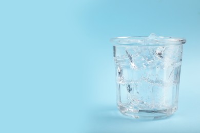 Photo of Glass of soda water with ice on light blue background. Space for text