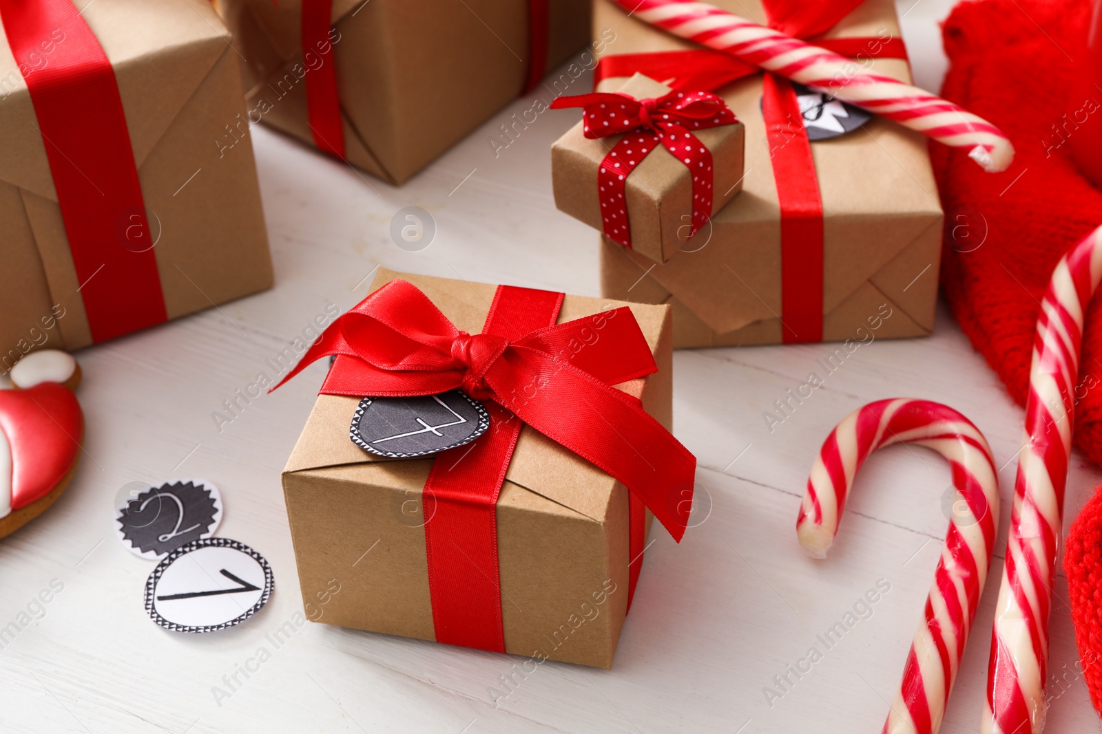 Photo of Gift boxes and Christmas candy canes on white wooden table. Advent calendar