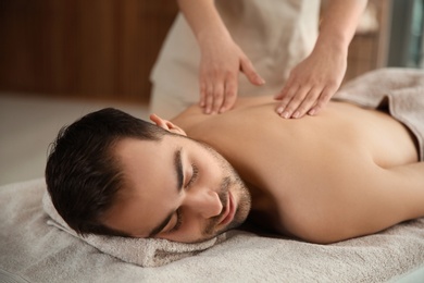 Photo of Handsome man receiving back massage in spa salon