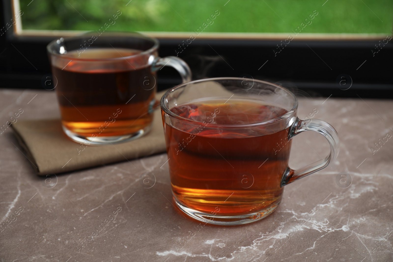 Photo of Cups of hot tea on grey marble windowsill