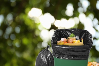 Waste bin and plastic bags full of garbage on blurred background, space for text