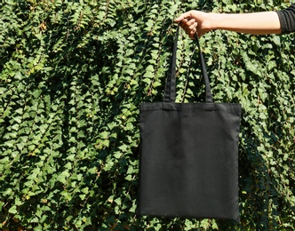 Photo of Woman holding eco bag outdoors, closeup. Mockup for design