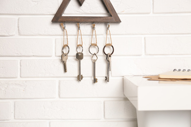 Photo of Wooden key holder on white brick wall indoors