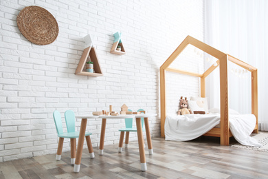 Photo of Cute children's room interior with bed and little table