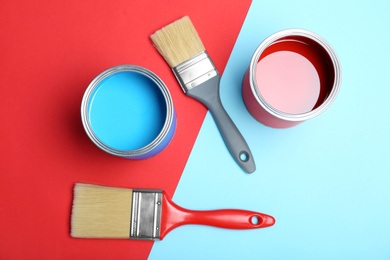 Photo of Flat lay composition with paint cans and brushes on color background