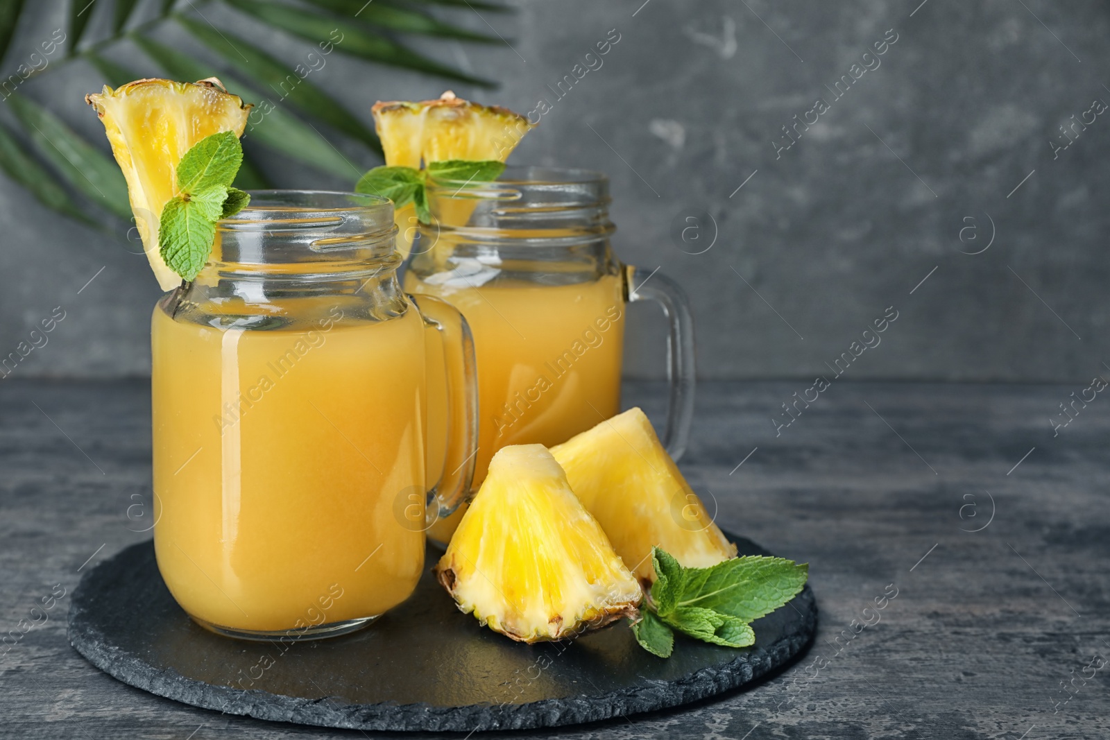 Photo of Mason jars with delicious pineapple juice on table