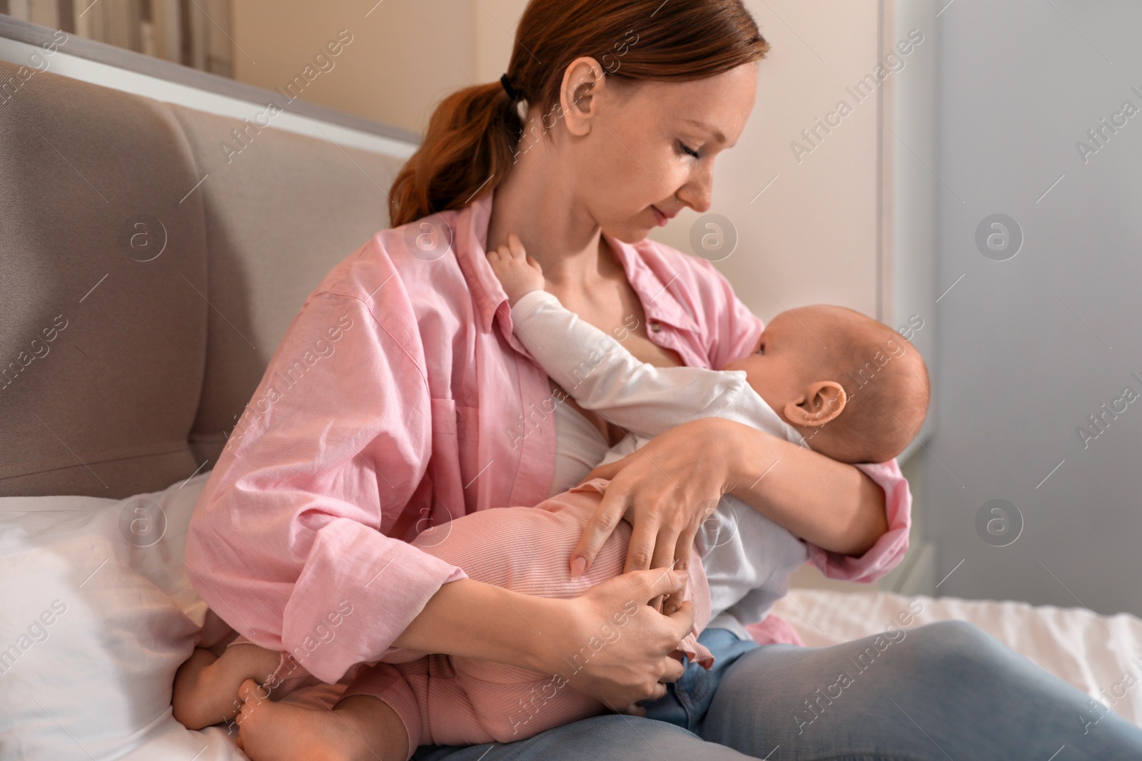 Photo of Young woman breast feeding her little baby in bedroom