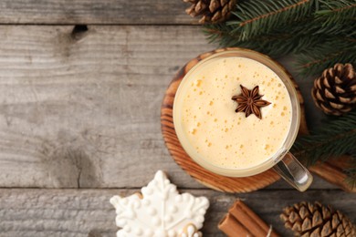 Photo of Cup of delicious eggnog with anise star on wooden table, flat lay. Space for text