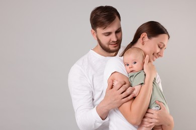 Photo of Happy family. Parents with their cute baby on grey background, space for text