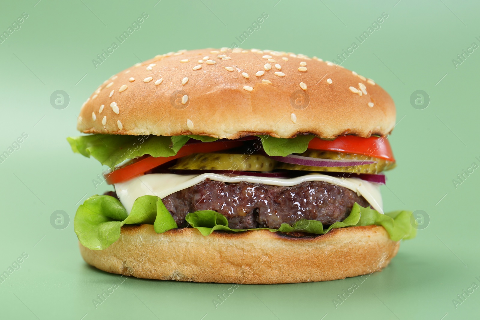 Photo of Burger with delicious patty on green background, closeup