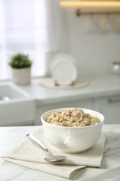 Breakfast time. Tasty oatmeal in bowl on white marble table. Space for text