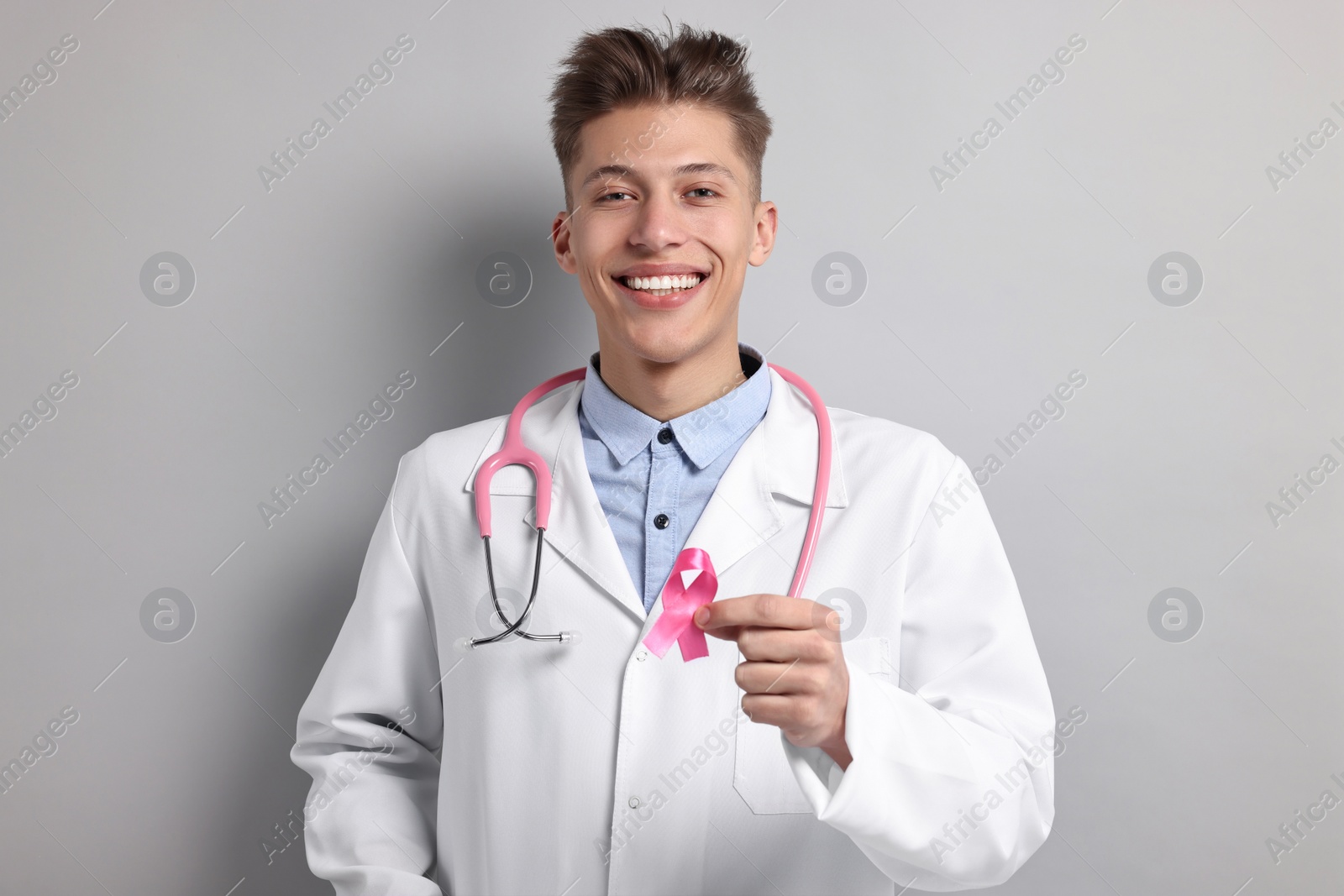 Photo of Mammologist with pink ribbon on light grey background. Breast cancer awareness