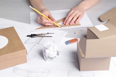 Woman creating packaging design at light wooden table, closeup