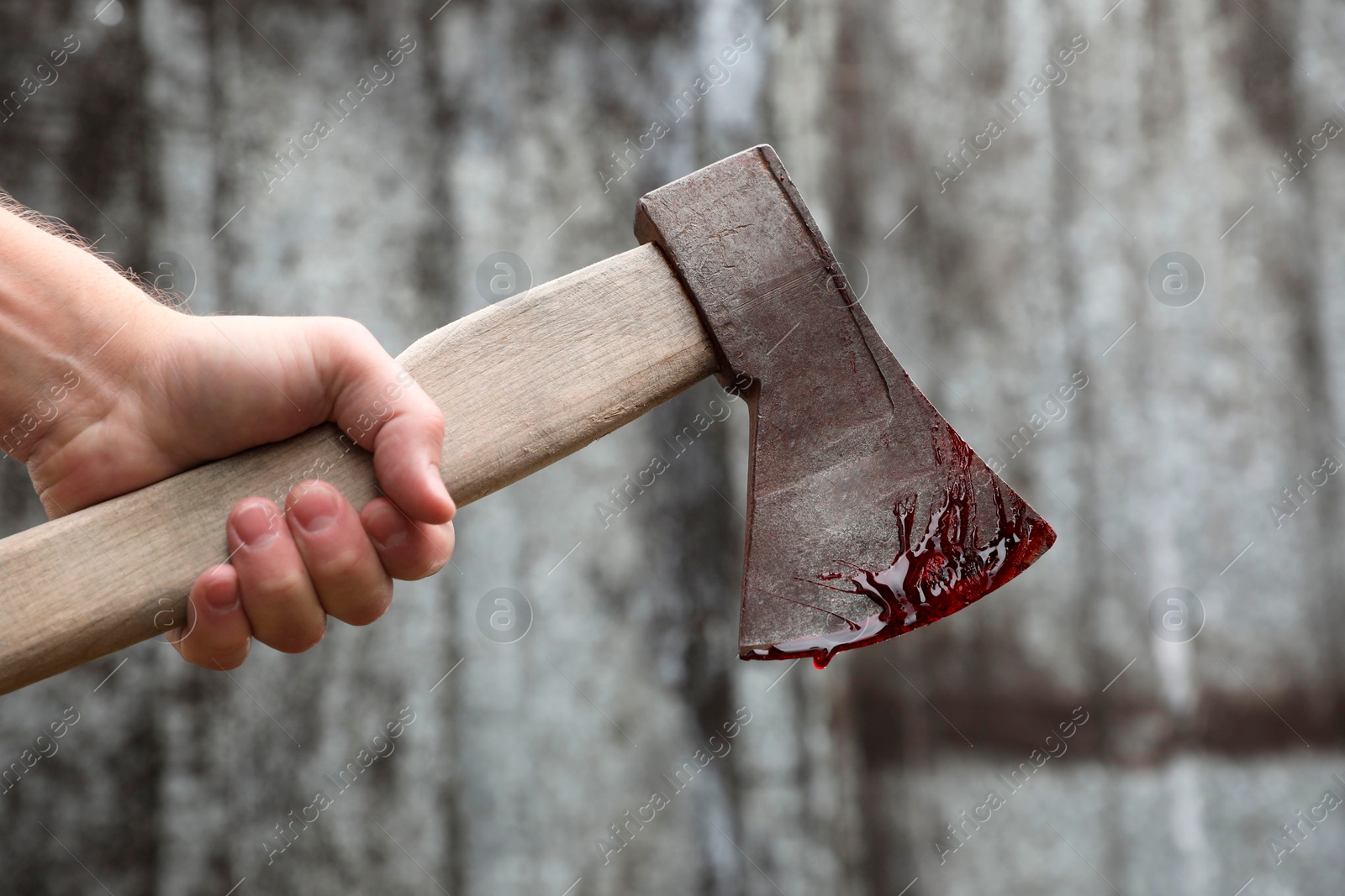 Photo of Man holding bloody axe outdoors, closeup view