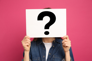 Photo of Woman holding question mark sign on pink background