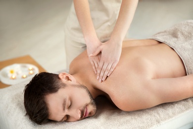 Photo of Handsome man receiving back massage in spa salon