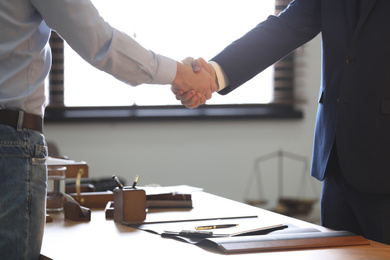 Photo of Male lawyer shaking hands with client in office, closeup