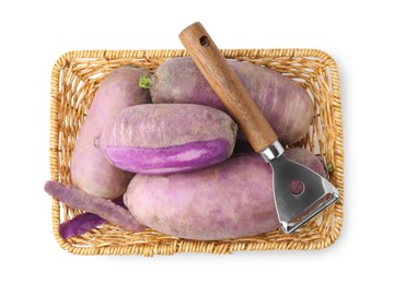 Photo of Purple daikon radishes and peeler in wicker basket isolated on white, top view