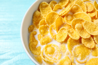 Tasty crispy corn flakes with milk on light blue table, closeup