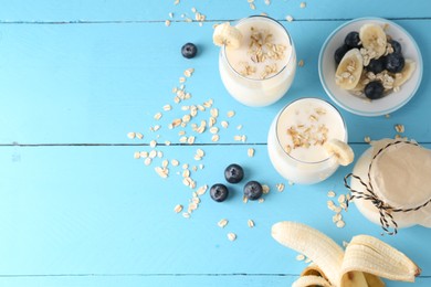 Tasty yogurt in glasses, oats, banana and blueberries on light blue wooden table, flat lay. Space for text