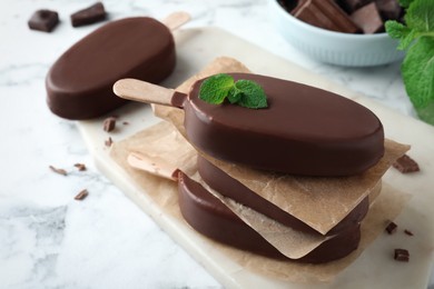 Delicious glazed ice cream bars with mint on white marble table