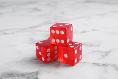Photo of Three red game dices on white marble table, closeup