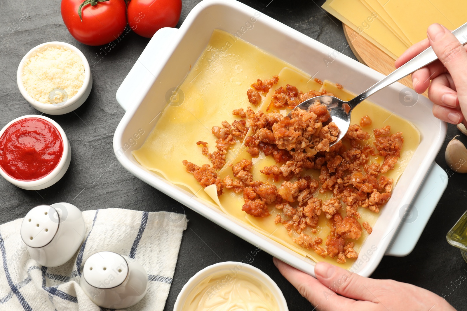 Photo of Woman making lasagna at dark table, top view