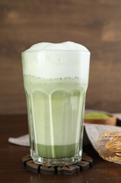 Photo of Glass of tasty matcha latte on wooden table