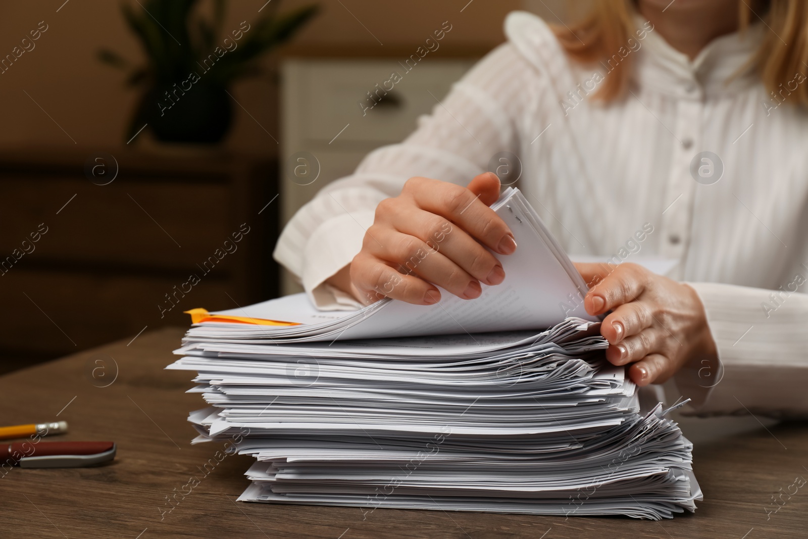 Photo of Woman stacking documents at wooden table indoors, closeup