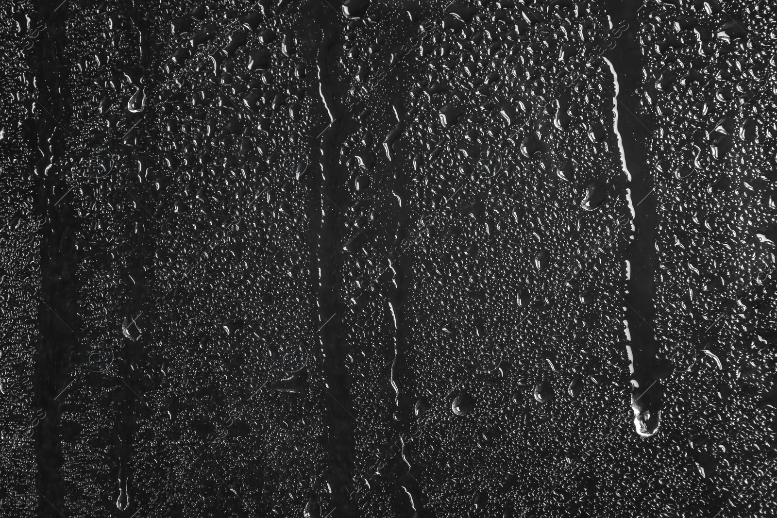 Photo of Glass with rain drops against dark background