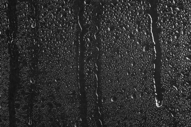 Photo of Glass with rain drops against dark background