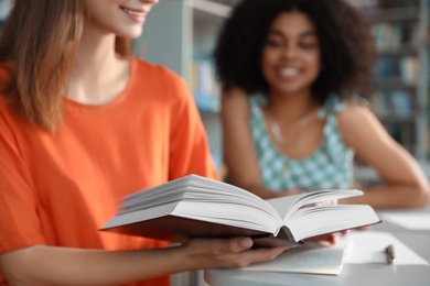 Young people studying at table in library, closeup