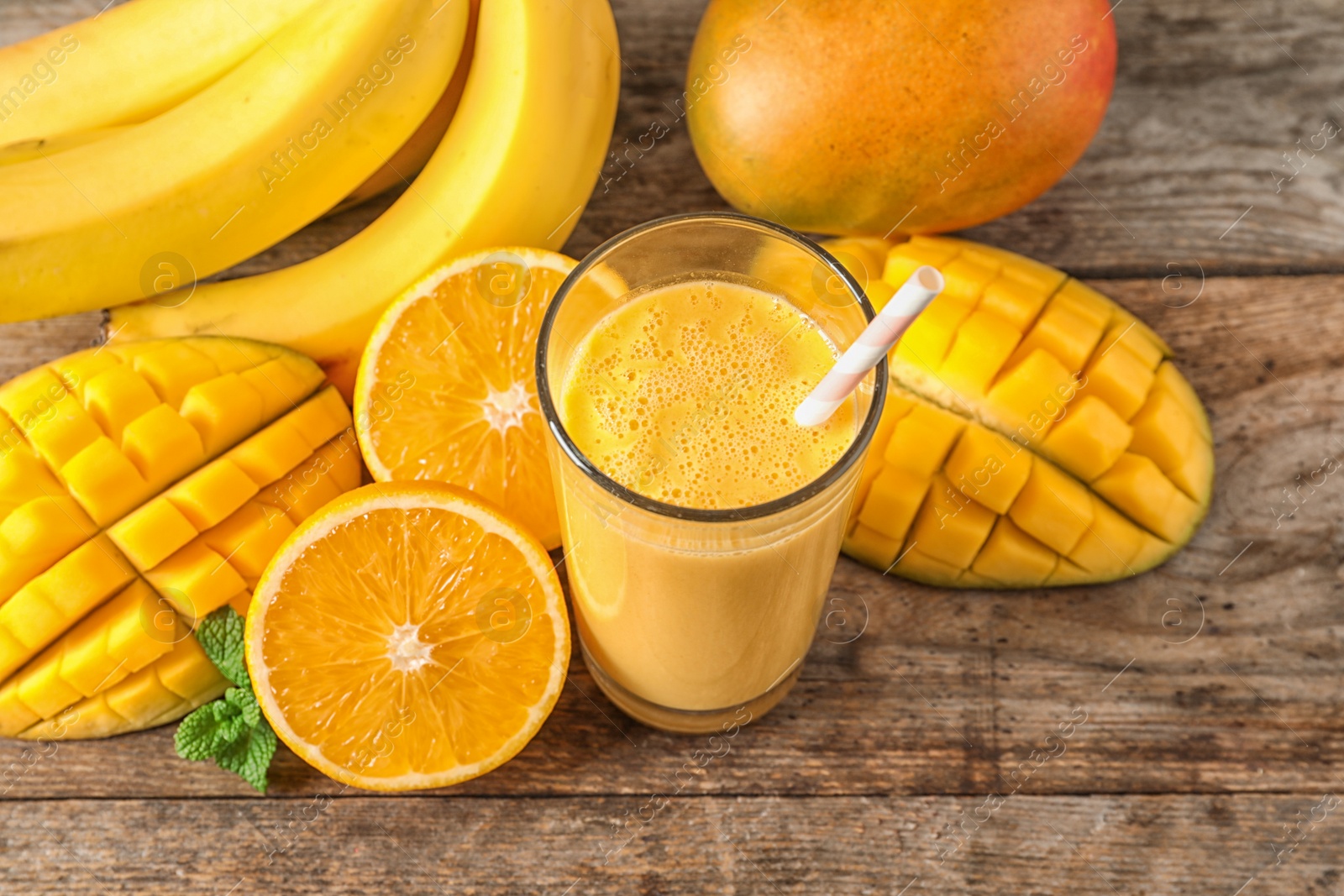 Photo of Tasty tropical drink with mango and fresh fruits on wooden table