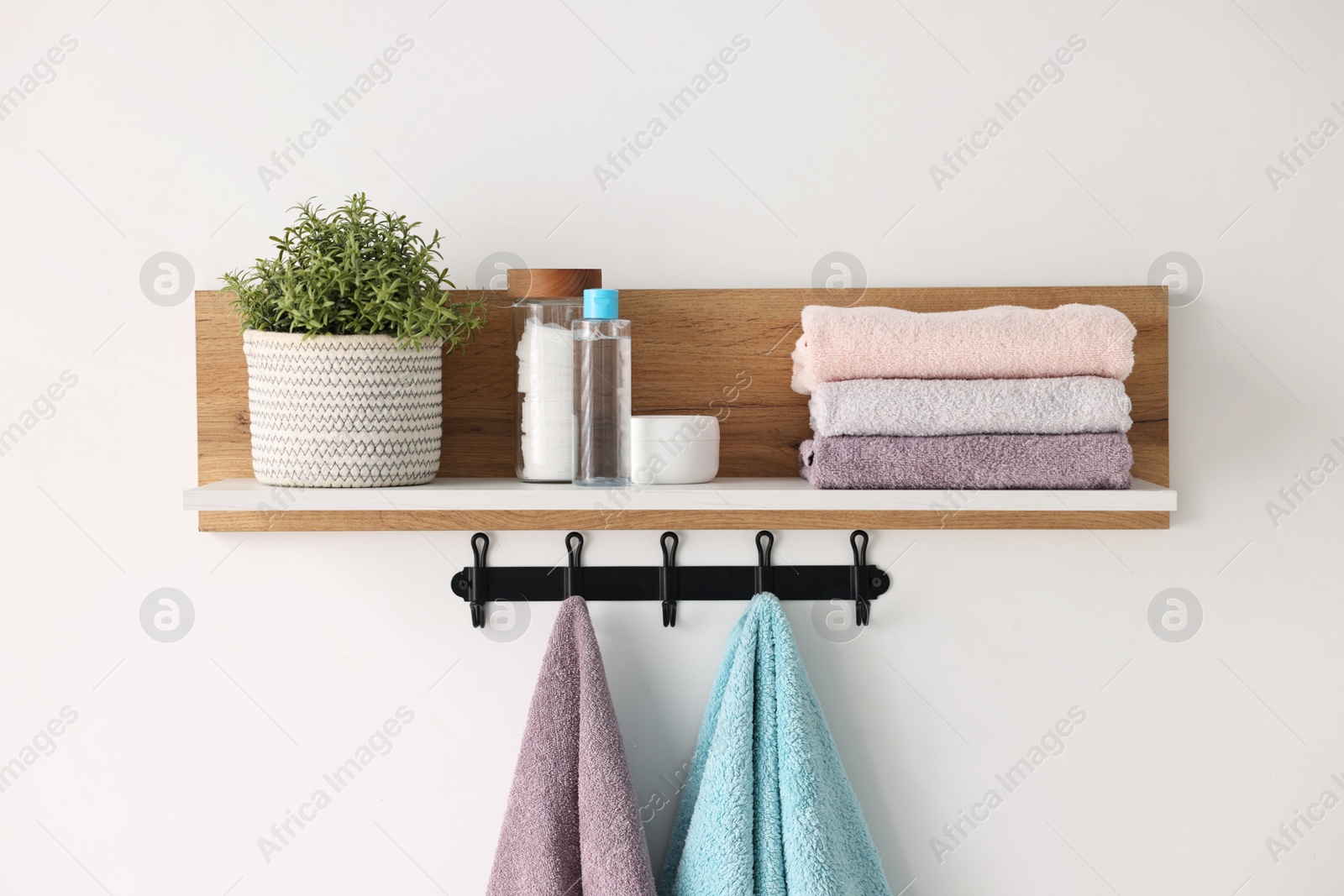 Photo of Clean towels, houseplant and toiletries on shelf indoors