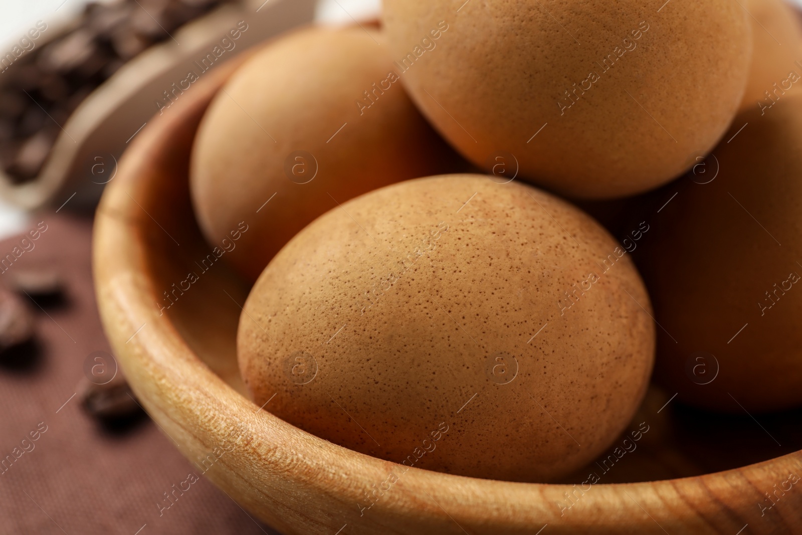 Photo of Easter eggs painted with natural dye in wooden bowl, closeup