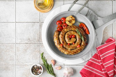 Photo of Delicious homemade sausage with garlic, tomatoes, rosemary and chili served on light tiled table, flat lay. Space for text