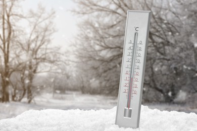 Thermometer showing temperature in snowy forest, winter weather