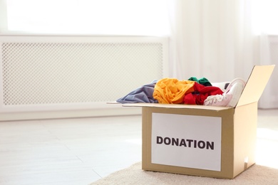 Photo of Carton box with donations on floor indoors. Space for text