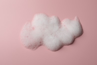 Photo of Drop of fluffy soap foam on pink background, top view