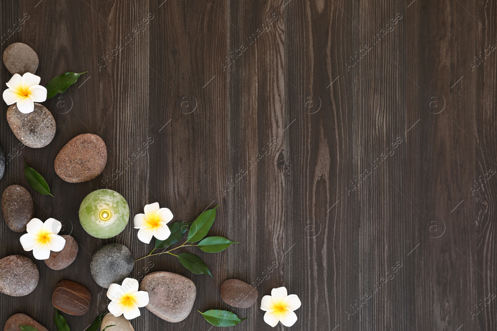 Photo of Flat lay composition with spa stones, flowers and candle on wooden background. Space for text