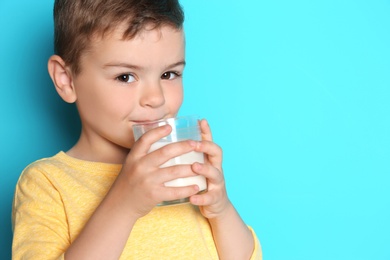 Photo of Cute little boy drinking milk on color background