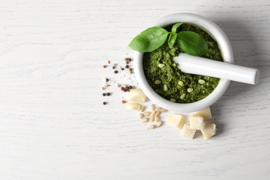 Photo of Flat lay composition with mortar of tasty pesto sauce and pestle on wooden table. Space for text