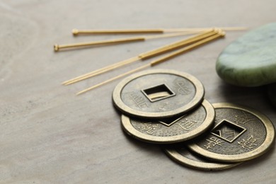 Acupuncture needles and Chinese coins on beige marble table, closeup. Space for text