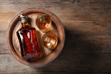 Photo of Barrel, bottle and glasses of tasty whiskey on wooden table, top view. Space for text
