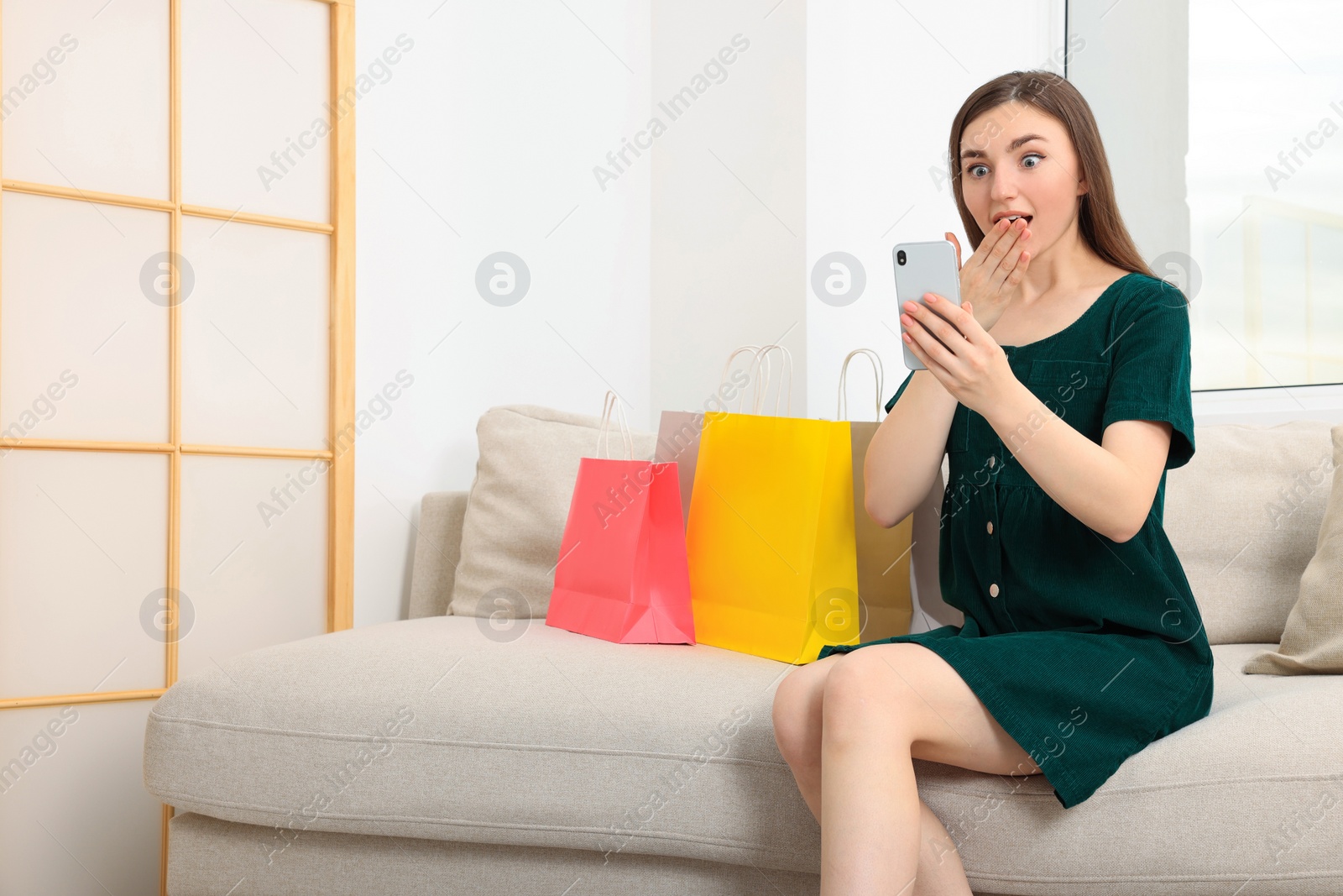 Photo of Special Promotion. Emotional woman looking at smartphone on sofa indoors. Space for text