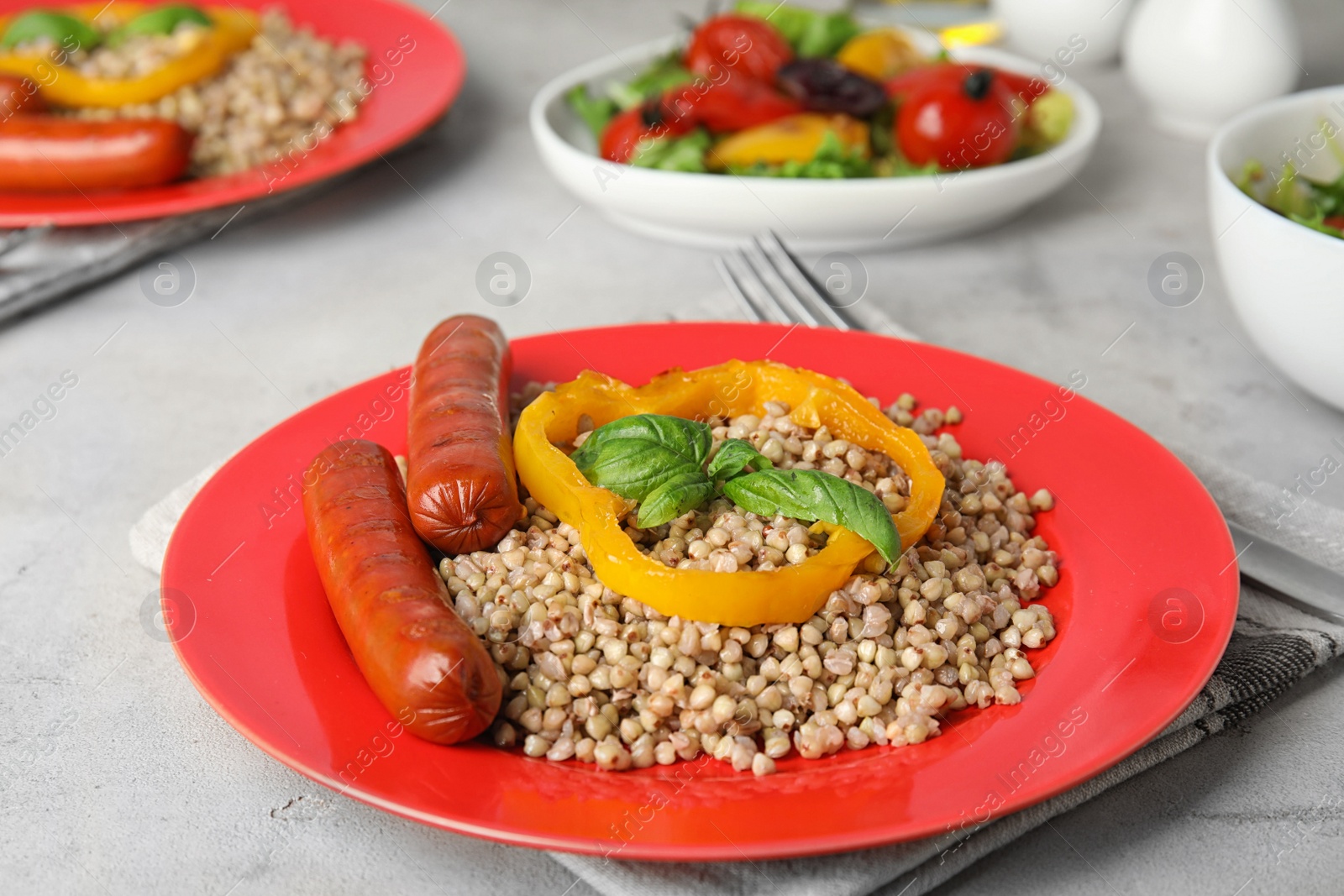 Photo of Tasty buckwheat porridge with sausages on light table