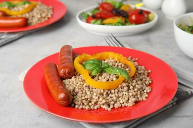 Photo of Tasty buckwheat porridge with sausages on light table