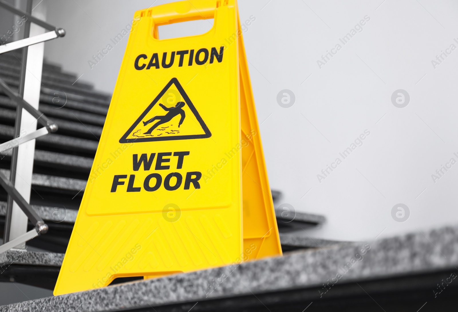 Photo of Safety sign with phrase Caution wet floor on stairs