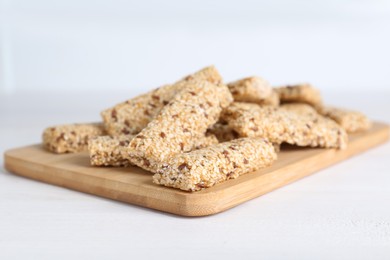 Photo of Tasty sesame seed bars on white wooden table