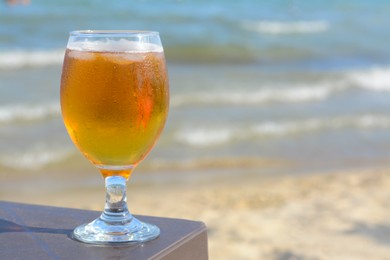 Cold beer in glass on beach. Space for text
